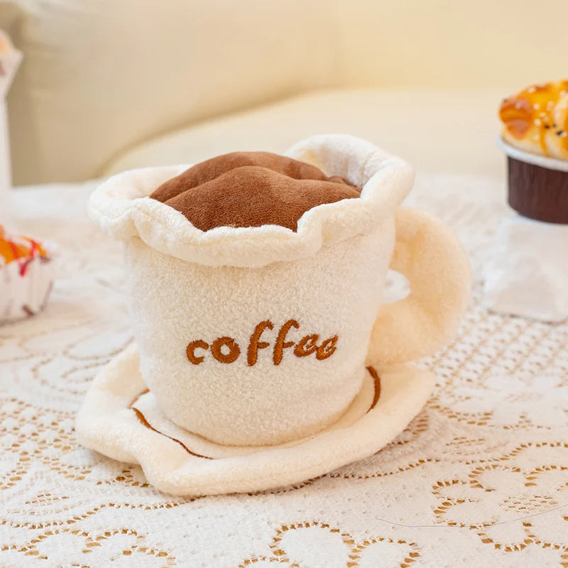 Plush toy resembling a coffee cup with a lid on a lace tablecloth.