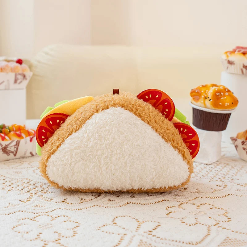 Plush sandwich shaped plush toy on a decorative tablecloth with a blurred background