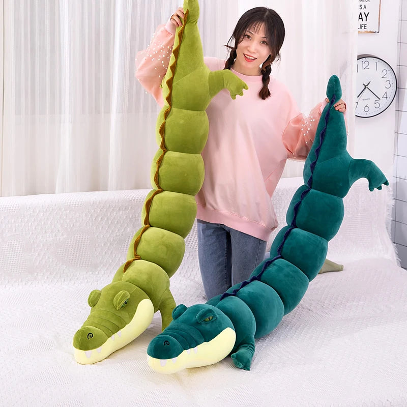 Person holding two long, segmented crocodile plush body pillows on a white couch