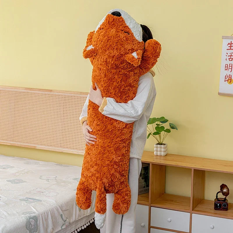 Person holding a large orange fox plush toy in a room with a bed and wooden shelf.