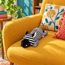 40cm / 16-inch black-and-white zebra plush body pillow resting on a mustard armchair, showing its compact size, rounded muzzle, upright ears and gray hooves.