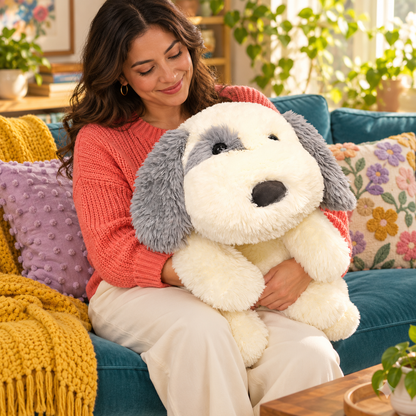 Adult holding the 65cm / 25.6-inch cream and gray sheepdog body pillow while seated on a teal sofa with colorful cushions.
