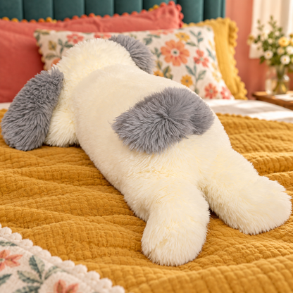 Rear view of the long sheepdog plush pillow showing its gray back patch, small gray tail, relaxed back legs, and cream shaggy coat.