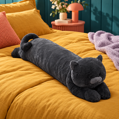 Full side profile of the charcoal-black cat body pillow lying unobstructed across a mustard bed with its rounded head, gray muzzle, small ears, long body, front paws, rear paws, and curled tail visible.