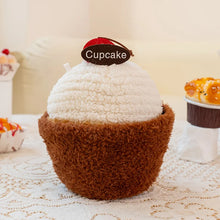 Plush toy shaped like a cupcake with a 'Cupcake' tag on a lace tablecloth.