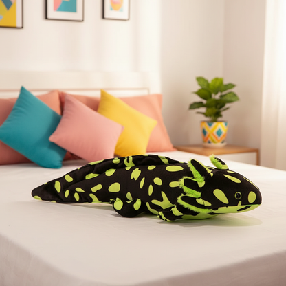 Plush lizard toy on a bed with colorful pillows and a plant in the background