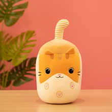 Cute cartoon boba cat plushie with a striped tail on a wooden surface and pink background