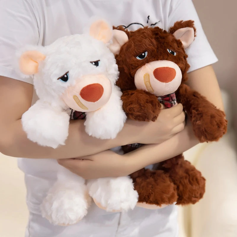 Two plush teddy bear toys, one white and one brown, held by a person against a neutral background.