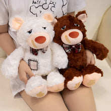 Two plush bear toys, one white and one brown, held by a person on a light background.