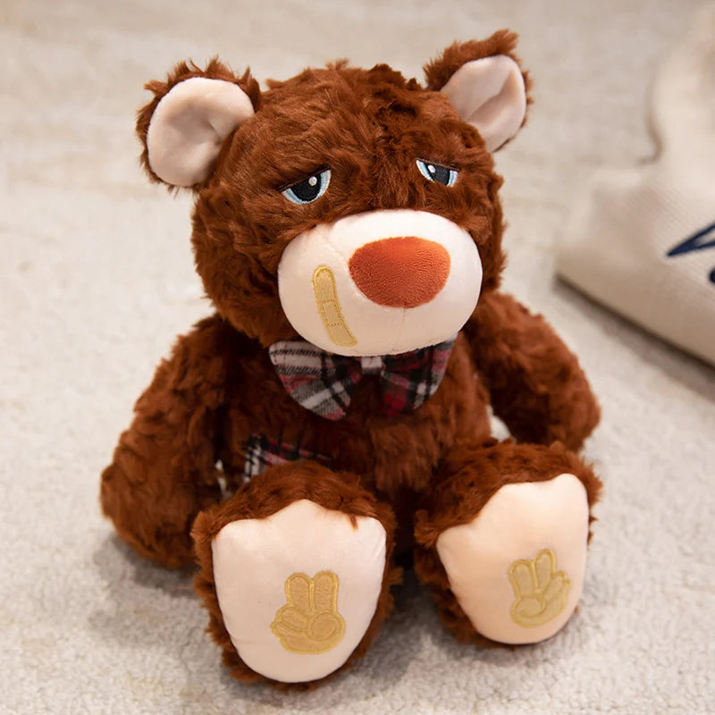 Brown teddy bear with a bow tie and bandaid on a light surface