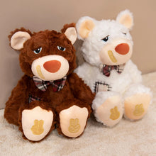 Two teddy bears, one brown and one white, sitting on a beige surface.