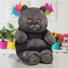 Gray cat plush toy with angry expression on a white surface with colorful background