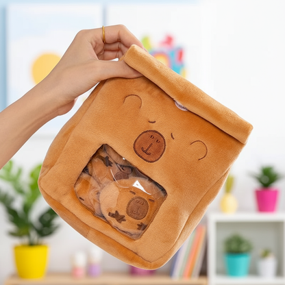 Person holding a brown plush bag with a bear design, containing more plush toys, against a blurred indoor background.
