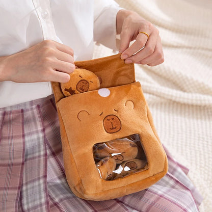 Person holding a plush capybara-shaped pouch with another capybata inside, on a checkered fabric background.