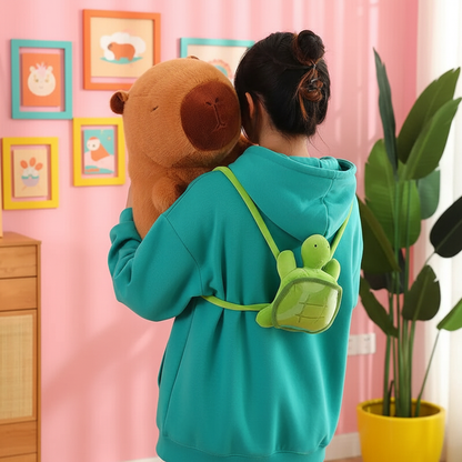 Person wearing a teal hoodie with a turtle design, holding a brown plush capybara in a room with pink walls and framed pictures.