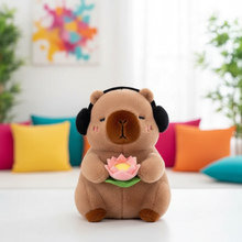Plush toy capybara with headphones and a flower on a colorful couch background
