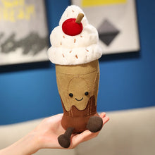 Plush toy resembling an ice cream cone with a smiley face held in a hand against a blue wall.