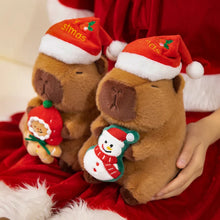 Two plush capybaras wearing Santa hats on a red fabric background