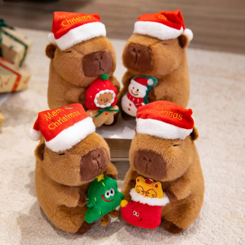 Four brown capybara plushies wearing Christmas hats and holding small Christmas-themed toys on a light background.