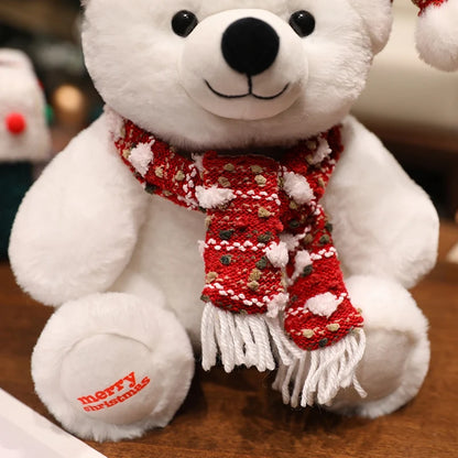 White teddy bear wearing a red Christmas scarf with 'merry christmas' text on a wooden surface.