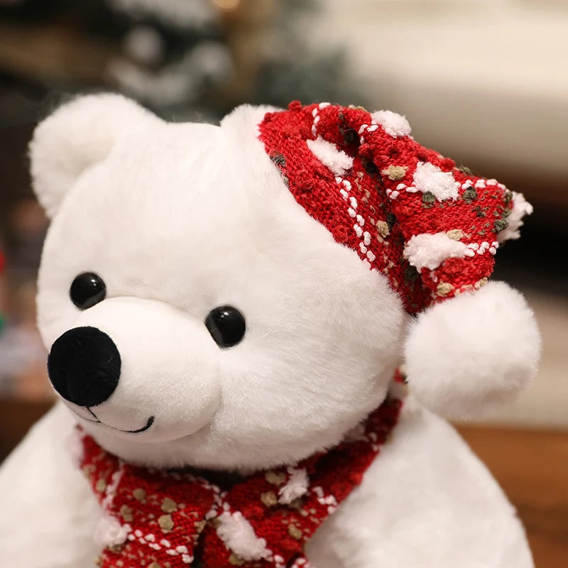 White teddy bear wearing a red and white patterned hat and scarf against a blurred background