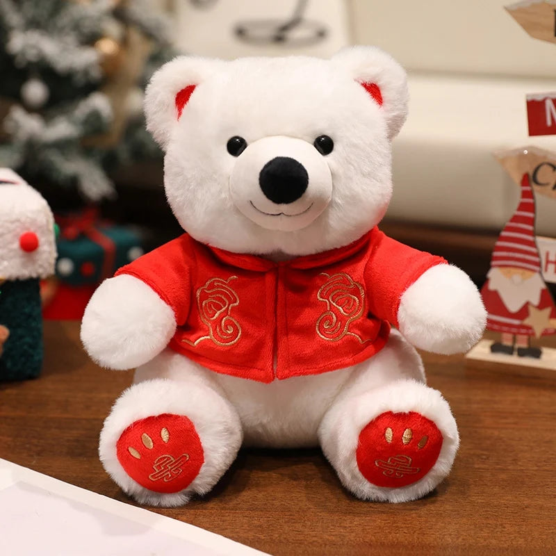 White teddy bear wearing a red outfit with gold patterns on a wooden surface.