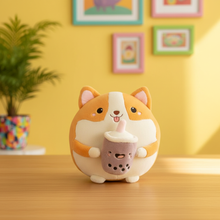 Cute plush toy resembling a corgi holding a cup on a wooden surface with a yellow wall and framed pictures in the background.
