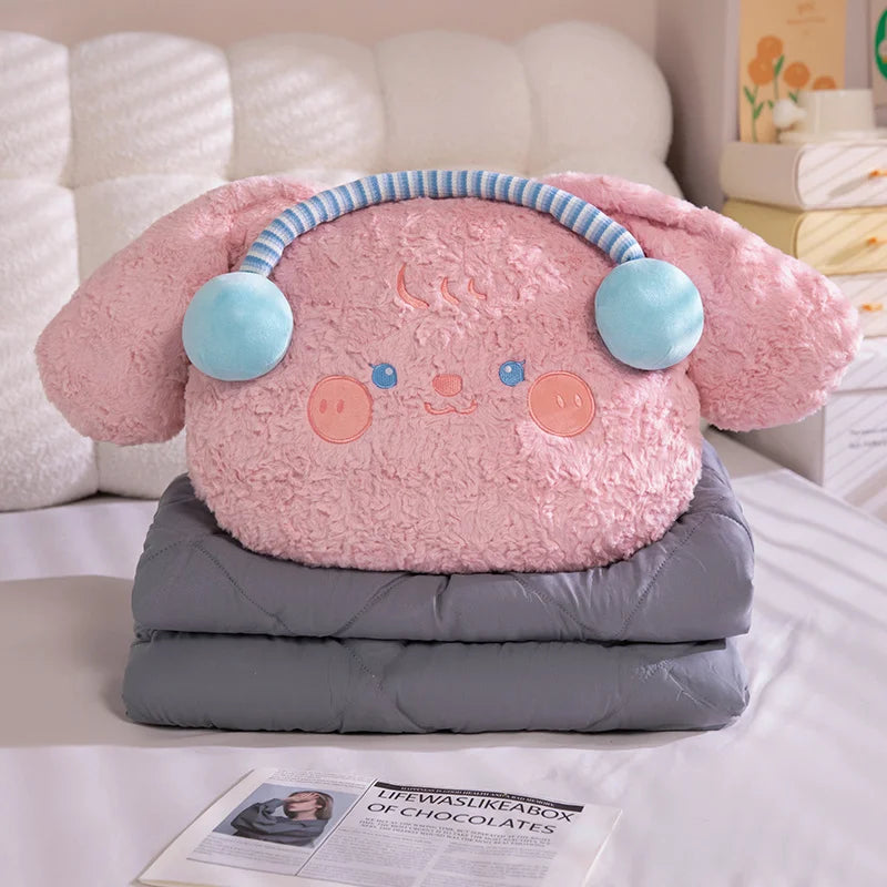 Pink plush toy with blue accents on a gray blanket on a bed