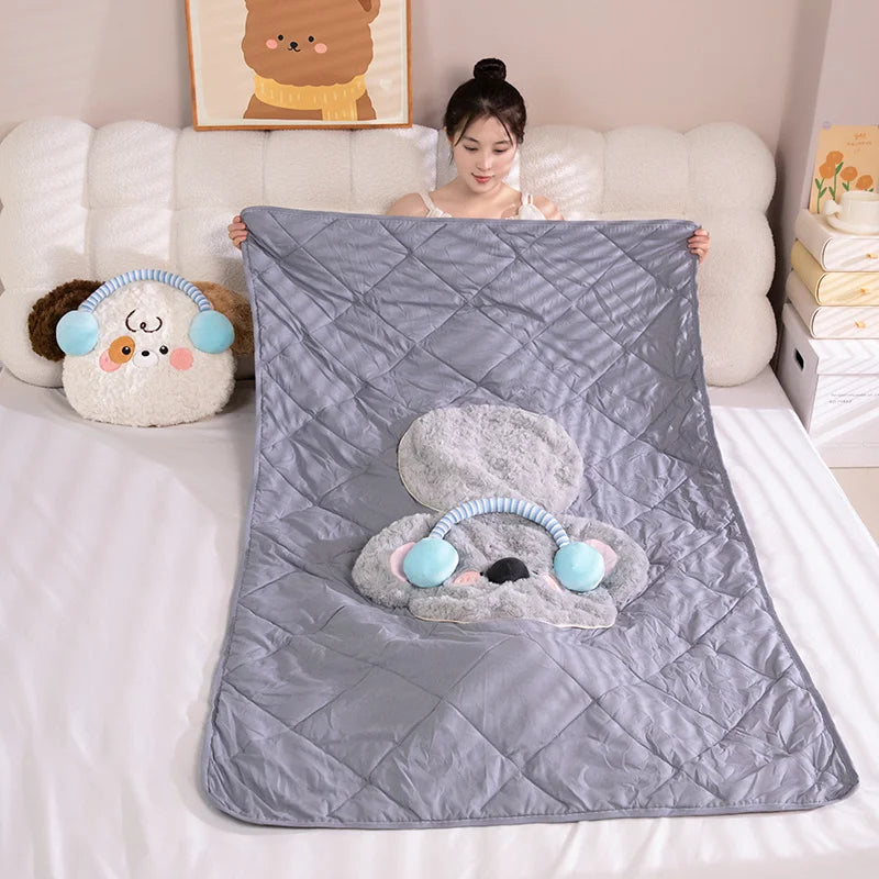 Person holding a gray quilt with cartoon character design on a bed