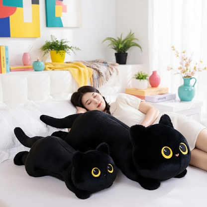Person lying on a bed with two large black cat plush toys