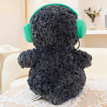 Plush penguin with green headphones on a light-colored surface