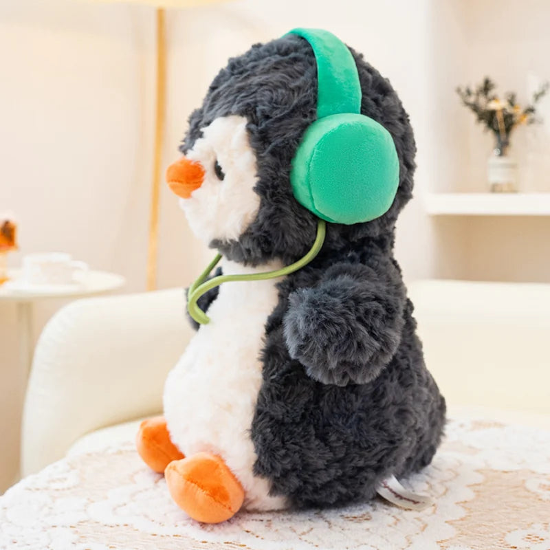 Plush toy penguin with green headphones on a soft surface