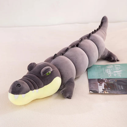 Gray crocodile plushie body pillow on a bed with a magazine underneath