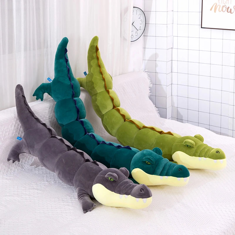 Three crocodile-shaped plushie body pillows in different colors on a white surface.