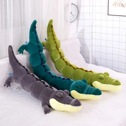 Three crocodile-shaped plushie body pillows in different colors on a white surface.