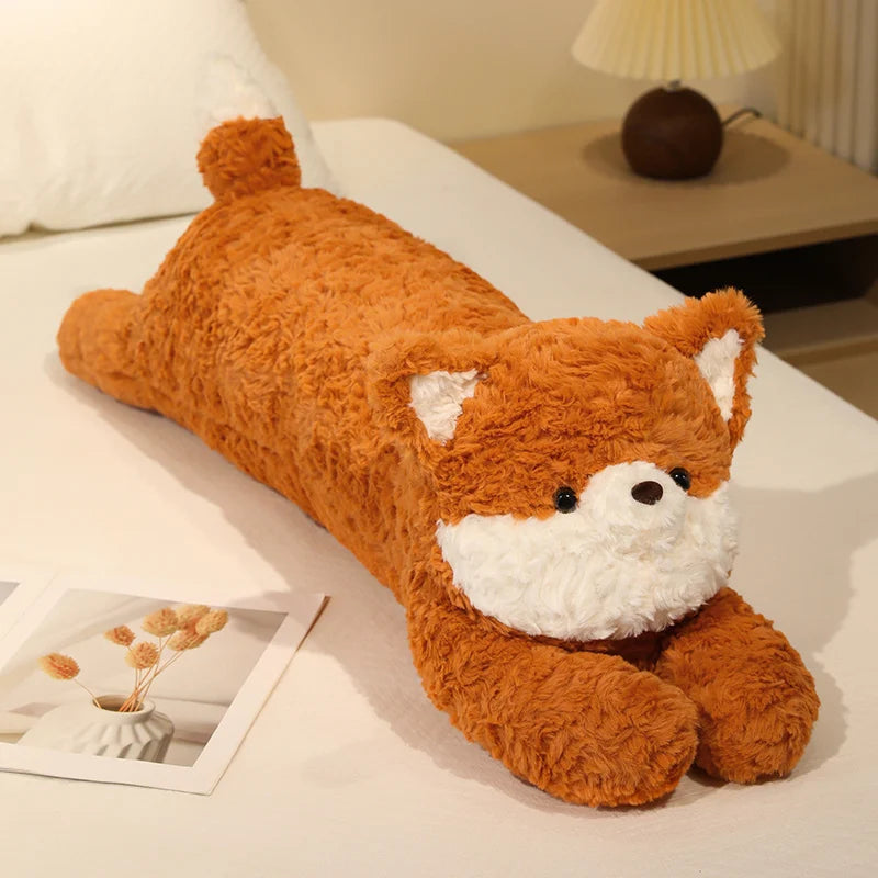 Plush toy shaped like a fox lying on a bed