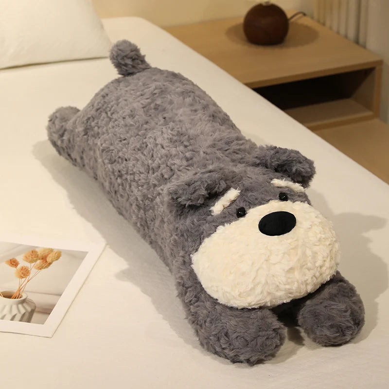 Gray plush toy shaped like a dog on a bed