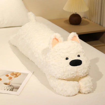 White plush dog toy on a bed with a lamp and decor in the background