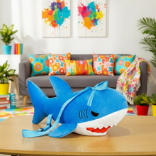 Blue shark plush backpack on a wooden table with a colorful living room in the background