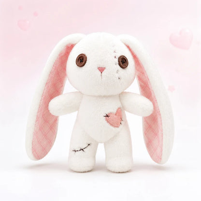 A white plush bunny toy with long floppy ears, brown button eyes, a pink stitched nose, and a pink heart patch on the chest, set against a soft pink background with faint heart shapes.
