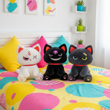 Three cartoon cat plush toys on a colorful bed with abstract patterns.