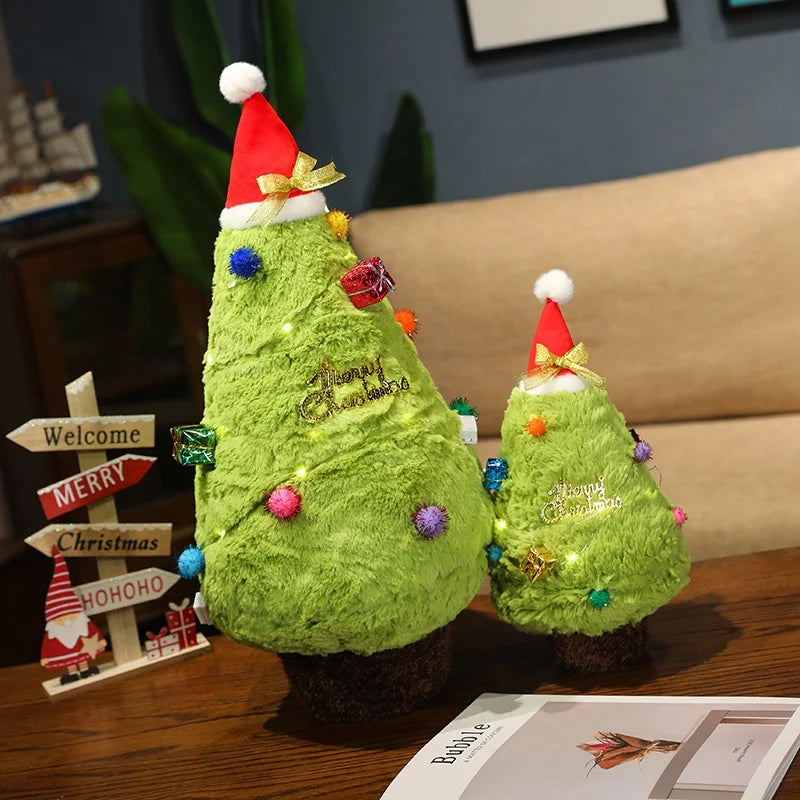 Two green plush Christmas trees with Santa hats on a wooden surface.