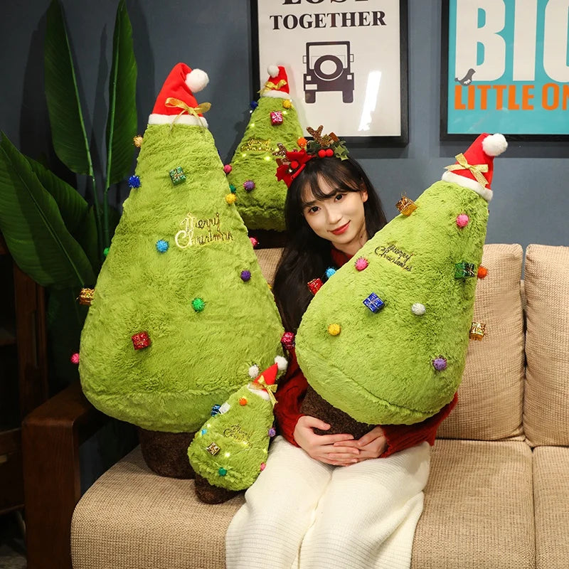 Person holding large green Christmas tree-shaped plush toys in a living room setting.
