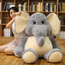 Child holding a large plush elephant toy in front of a bookshelf