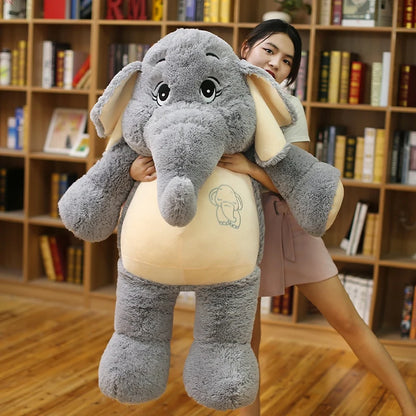 Person holding a large plush elephant toy in a room with bookshelves.