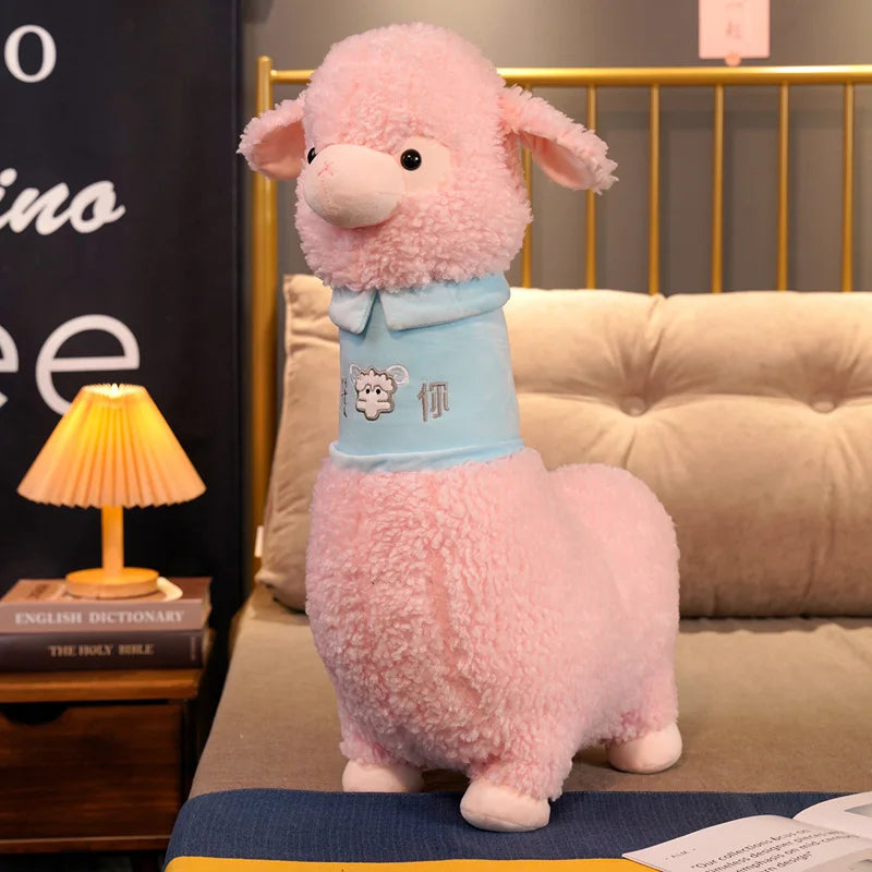 Pink plush toy resembling a sheep with a blue shirt on a couch