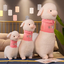 Three plush sheep toys with pink outfits on a decorative surface.