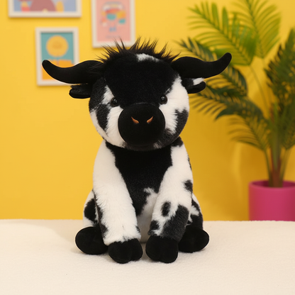 A black and white plush cow toy with small horns, sitting on a white surface against a bright yellow wall with framed art and a potted plant in the background.