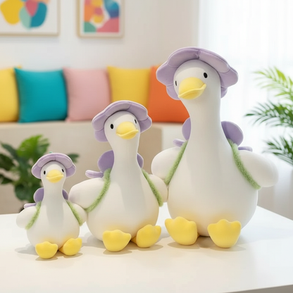 Three plush duck toys with purple hats on a white surface, colorful pillows in the background.