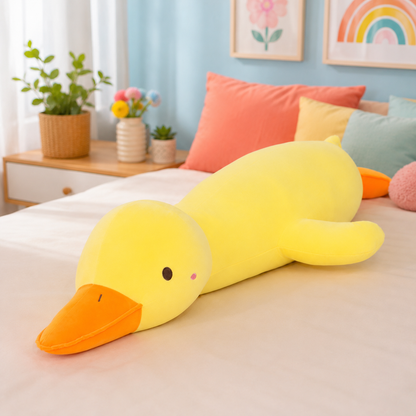 A large yellow duck-shaped plush body pillow with an orange beak lies stretched across a bed in a bright, pastel bedroom. The room includes colorful pillows, potted plants, and framed wall art.